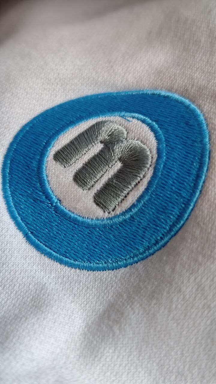 Round blue logo embroidered on white textile